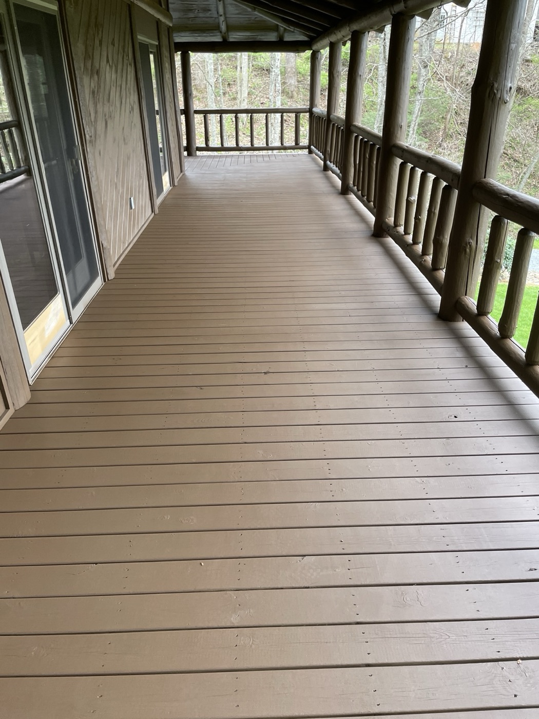 Long covered porch with composite decking and log rails