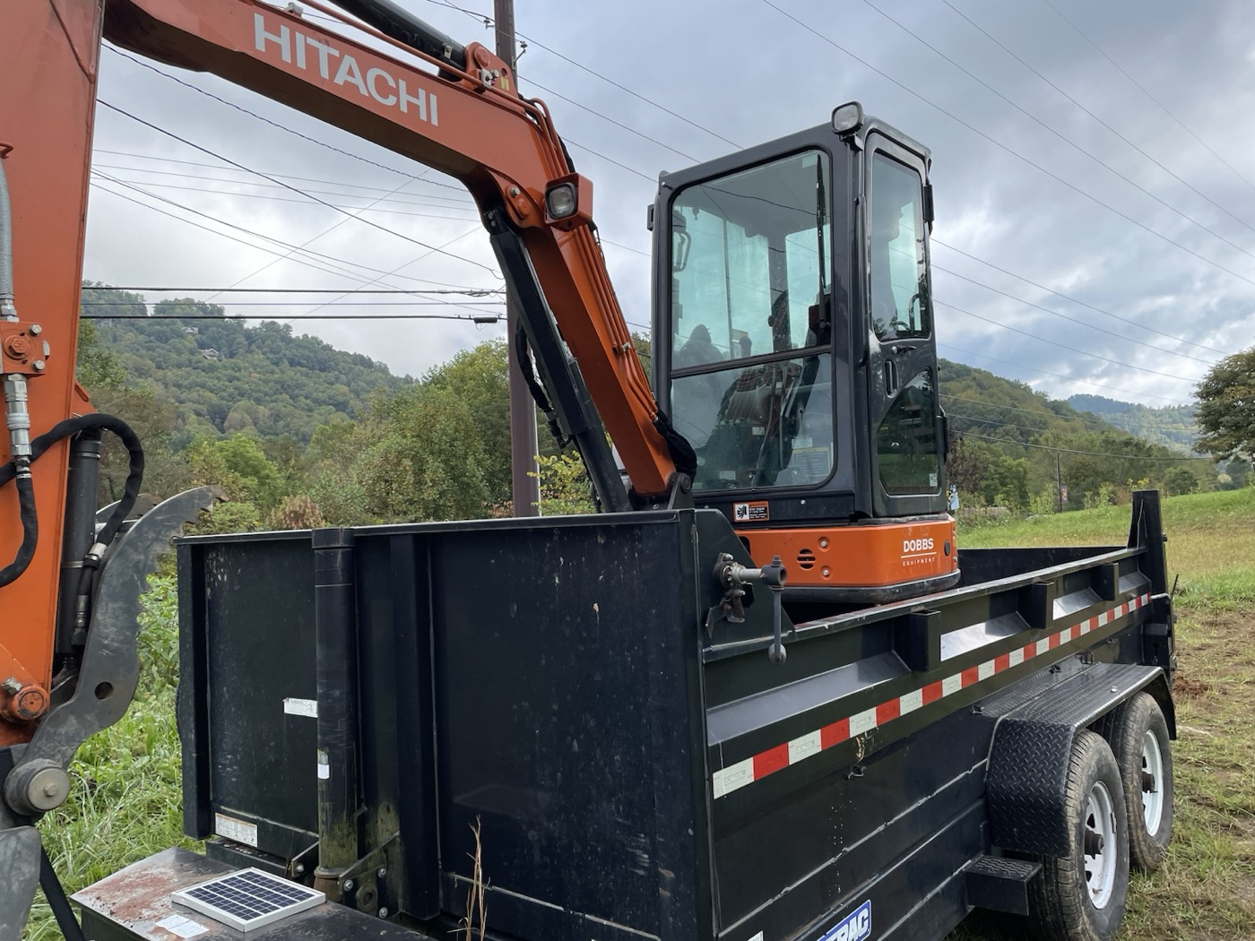 Excavator and dump trailer with mountains in the distance