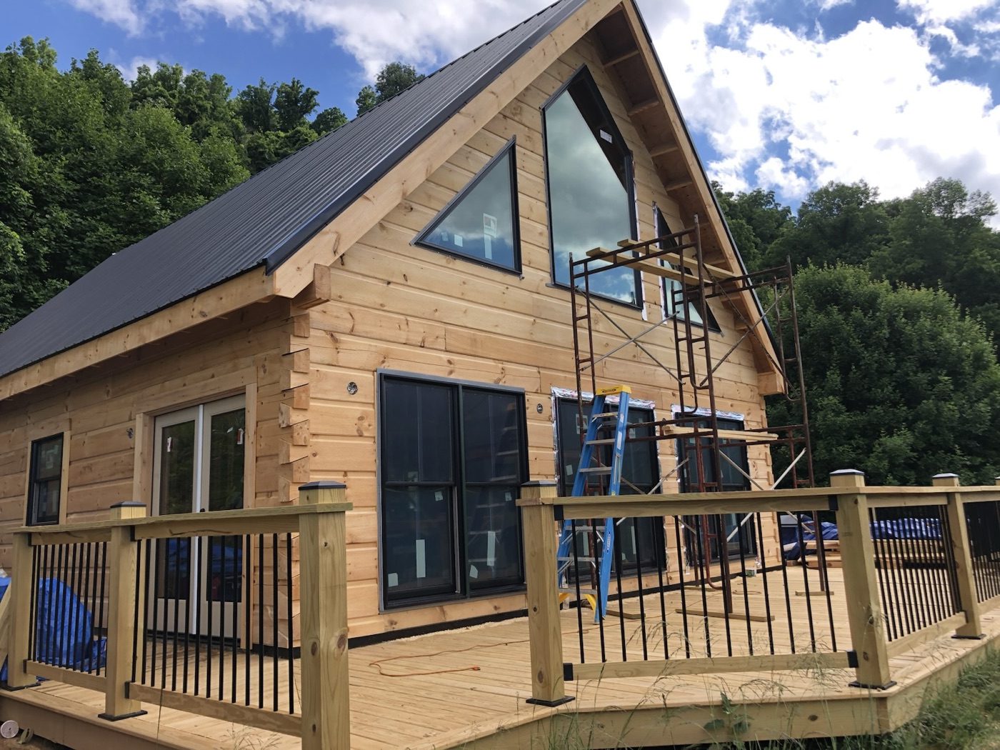 New log home with a large gable window and a wraparound deck