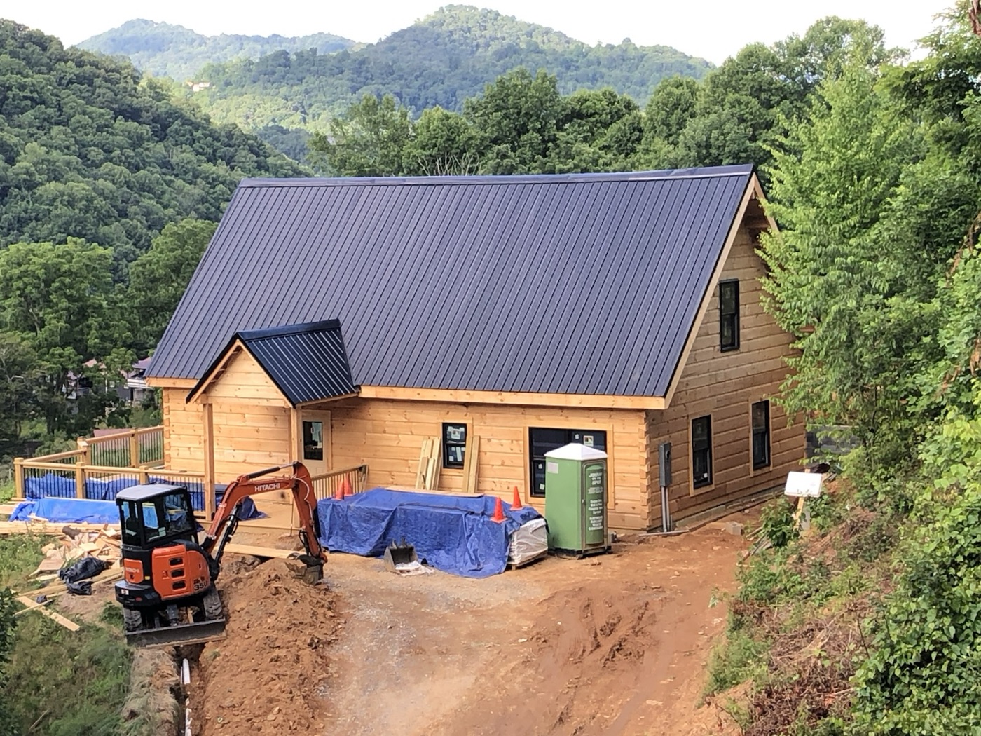 Log home going up with the mountains behind it and an excavator working out front